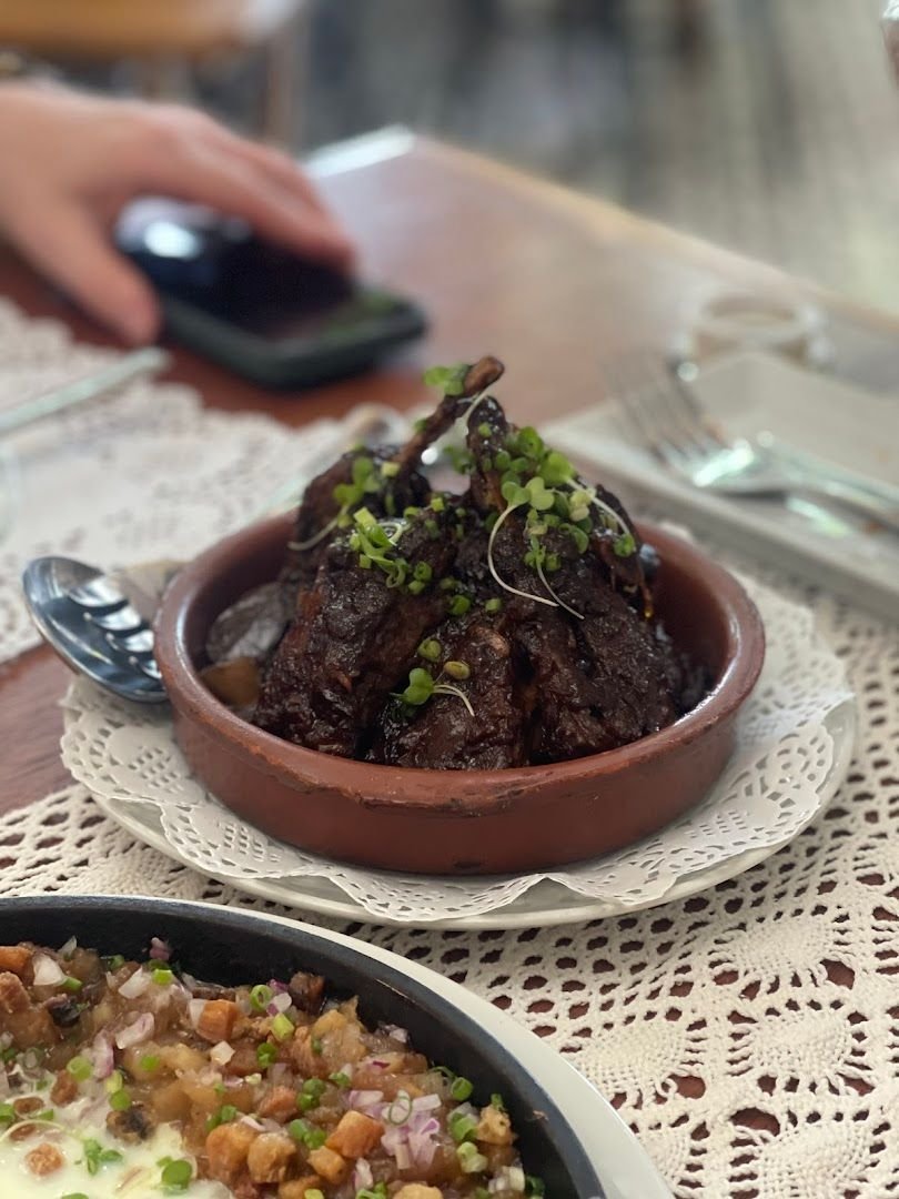 Lamb Adobo braised in terracotta dish with microgreens