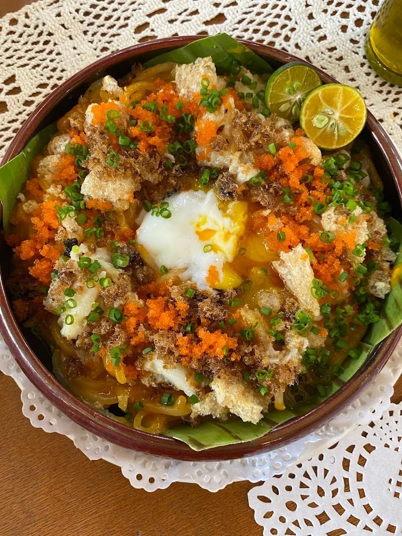 Palabok with egg, tobiko, chicharon, and calamansi on lace doily